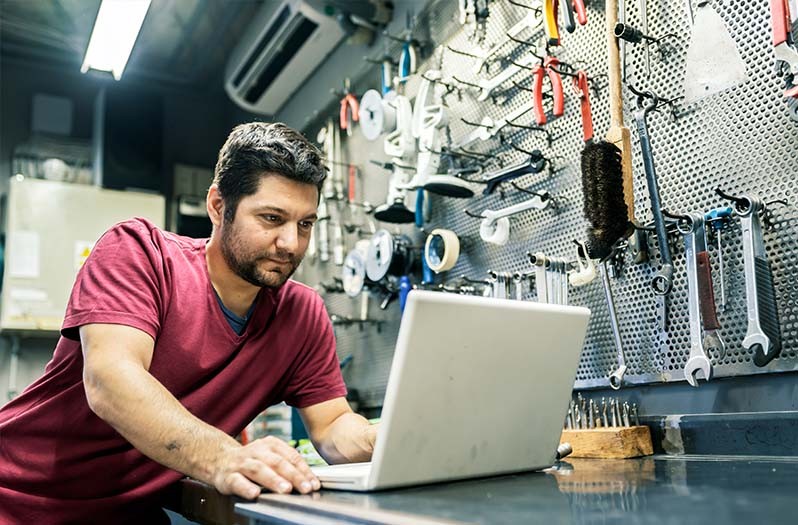 Ein Autowerkstattmitarbeiter, der auf seinem Computer die HELLA TECH WORLD aufruft. 